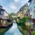 brown and white concrete buildings beside river under white clouds during daytime